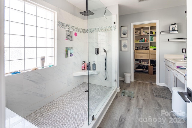 bathroom with a tile shower, vanity, and hardwood / wood-style flooring