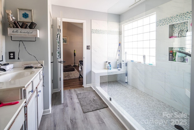 bathroom with hardwood / wood-style floors, vanity, and a tile shower