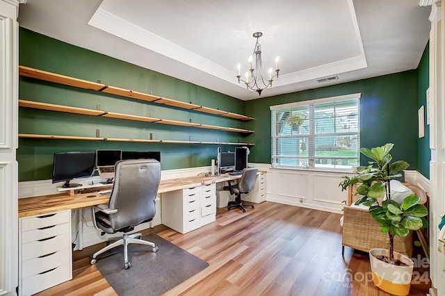 office featuring a tray ceiling, an inviting chandelier, light hardwood / wood-style floors, and crown molding