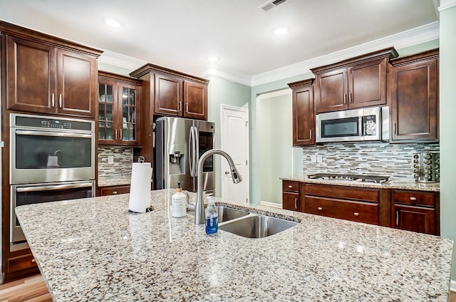 kitchen featuring light stone counters, crown molding, appliances with stainless steel finishes, sink, and light hardwood / wood-style flooring