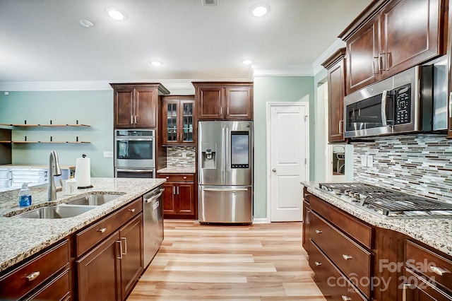 kitchen featuring appliances with stainless steel finishes, sink, ornamental molding, and light hardwood / wood-style flooring