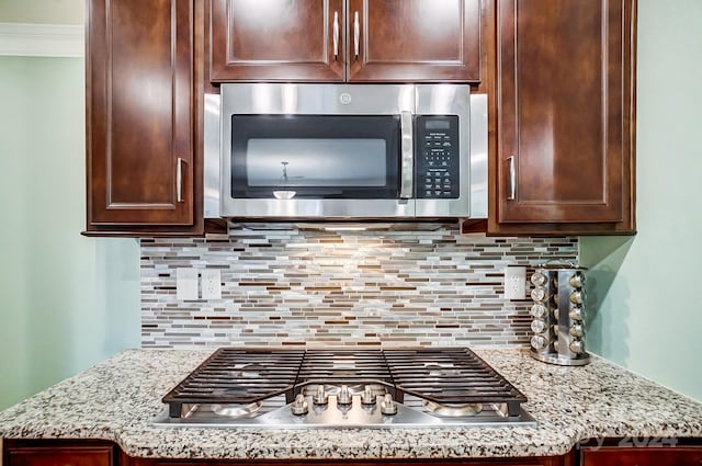 kitchen featuring appliances with stainless steel finishes, light stone counters, and backsplash