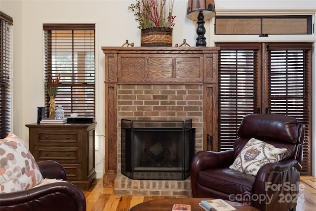 sitting room with a brick fireplace and light wood-type flooring