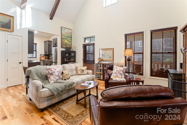 living room with beam ceiling, light wood-type flooring, high vaulted ceiling, and a healthy amount of sunlight