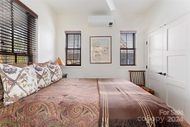 bedroom featuring a closet, a wall mounted air conditioner, and multiple windows