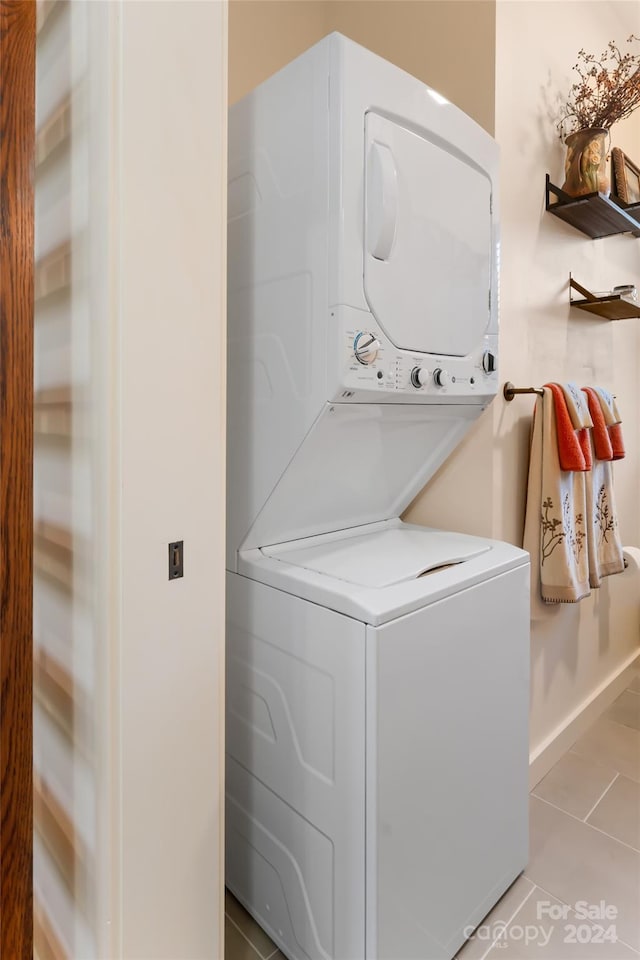 laundry room featuring stacked washer / dryer and light tile patterned flooring