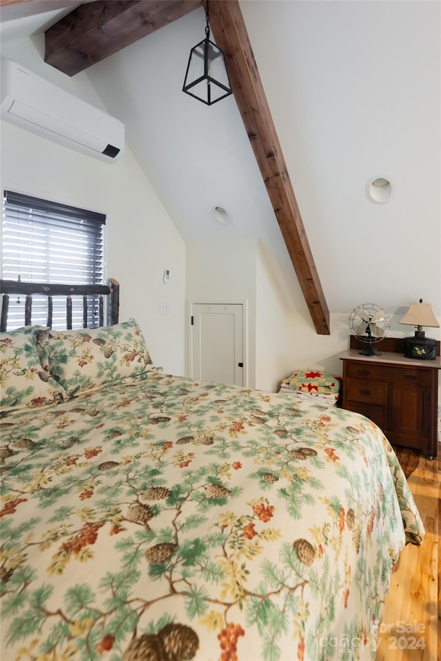 bedroom with a wall mounted air conditioner, vaulted ceiling with beams, and light hardwood / wood-style flooring