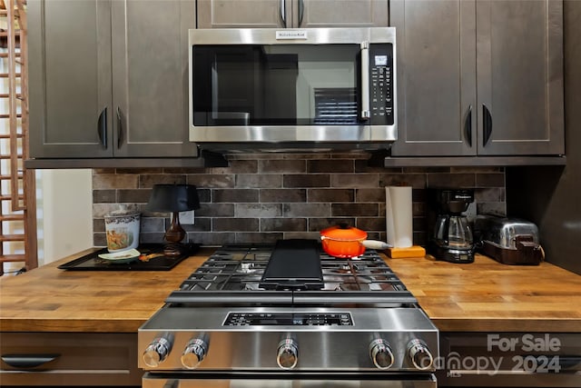 kitchen with butcher block countertops, gray cabinets, decorative backsplash, and appliances with stainless steel finishes