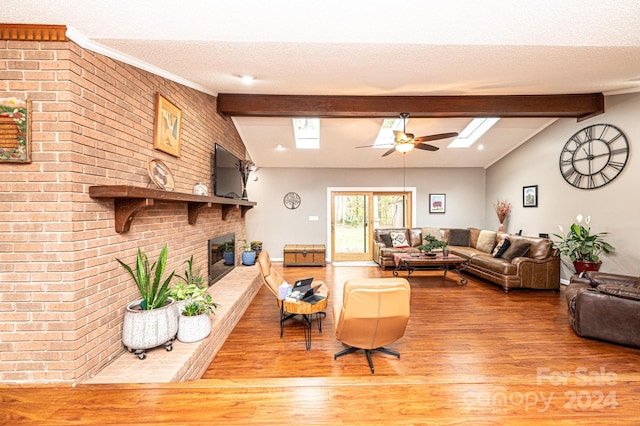 living room featuring lofted ceiling with beams, a textured ceiling, hardwood / wood-style flooring, a brick fireplace, and ceiling fan