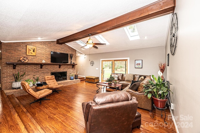 living room with a fireplace, light wood-type flooring, a textured ceiling, lofted ceiling with skylight, and ceiling fan