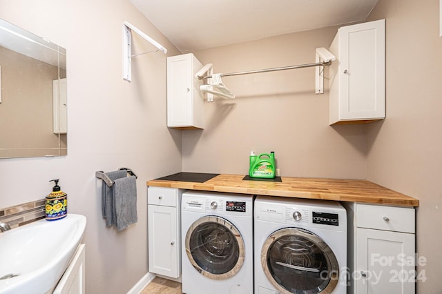 clothes washing area featuring washing machine and clothes dryer, cabinets, and sink