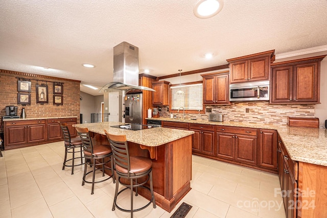 kitchen featuring island range hood, ornamental molding, stainless steel appliances, a kitchen island, and a breakfast bar