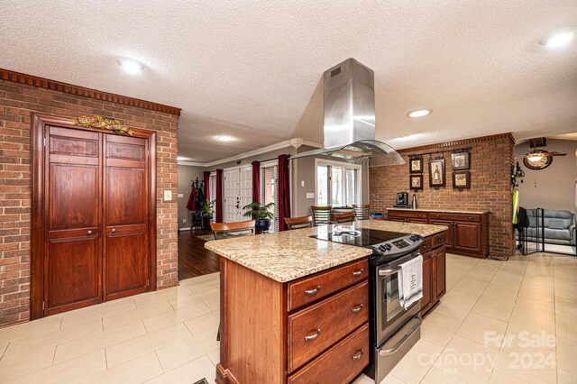 kitchen with brick wall, island range hood, and electric stove