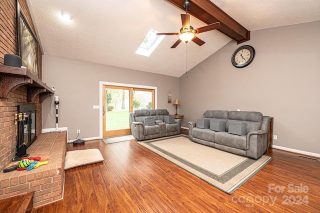 living room with hardwood / wood-style flooring, a textured ceiling, lofted ceiling with skylight, and ceiling fan