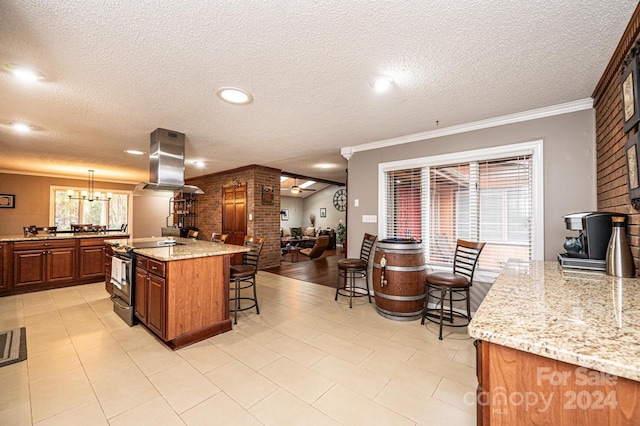 kitchen with island range hood, an inviting chandelier, a breakfast bar area, light stone countertops, and decorative light fixtures