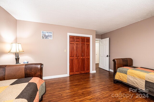 bedroom featuring dark hardwood / wood-style flooring, a textured ceiling, and a closet