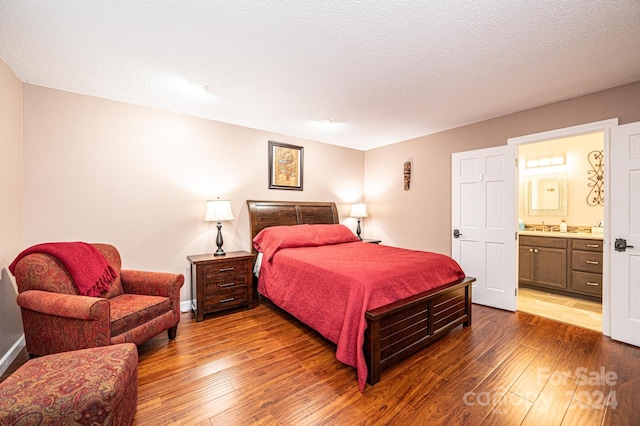 bedroom with ensuite bathroom, a textured ceiling, and dark hardwood / wood-style flooring