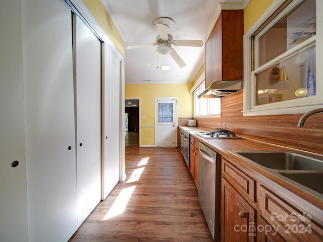 kitchen featuring sink, stainless steel appliances, light hardwood / wood-style flooring, butcher block countertops, and crown molding