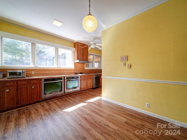 kitchen with hanging light fixtures, crown molding, light hardwood / wood-style flooring, ceiling fan, and appliances with stainless steel finishes