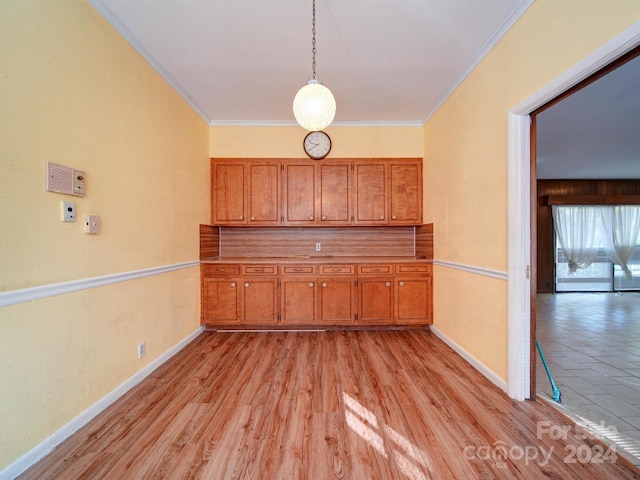 kitchen with crown molding, pendant lighting, and light hardwood / wood-style floors