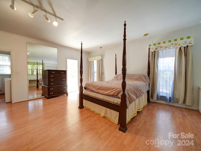 bedroom with hardwood / wood-style floors, track lighting, and ornamental molding