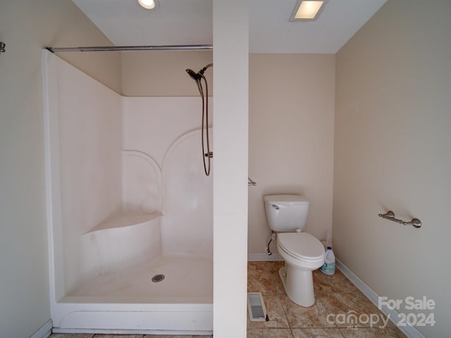 bathroom featuring tile patterned flooring, toilet, and walk in shower