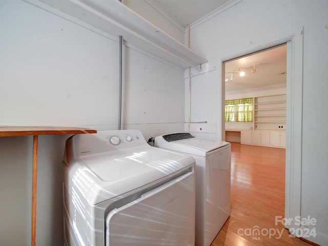 clothes washing area with separate washer and dryer, crown molding, and light hardwood / wood-style flooring