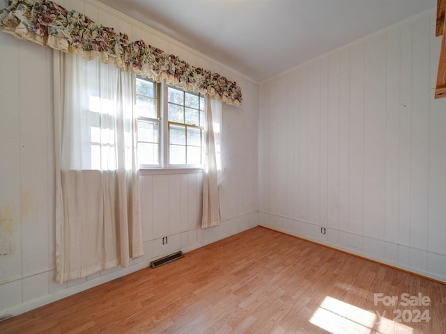 empty room featuring wooden walls and light wood-type flooring