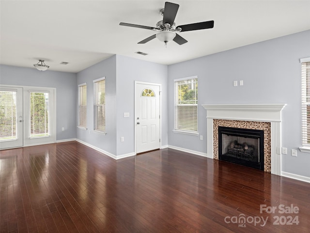 unfurnished living room with ceiling fan, a tile fireplace, and dark hardwood / wood-style floors