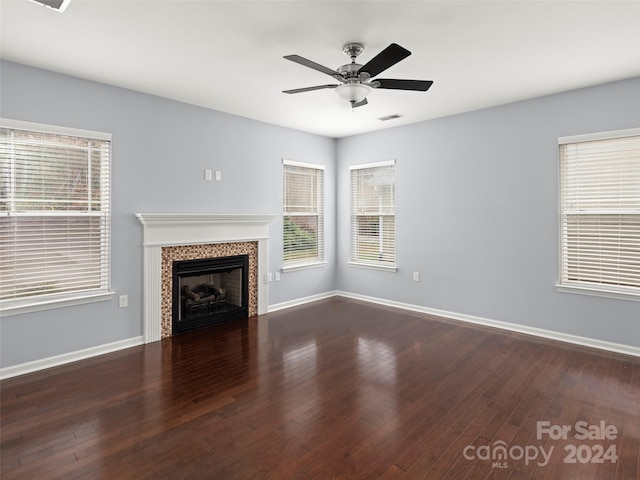 unfurnished living room featuring a fireplace, dark hardwood / wood-style flooring, and ceiling fan