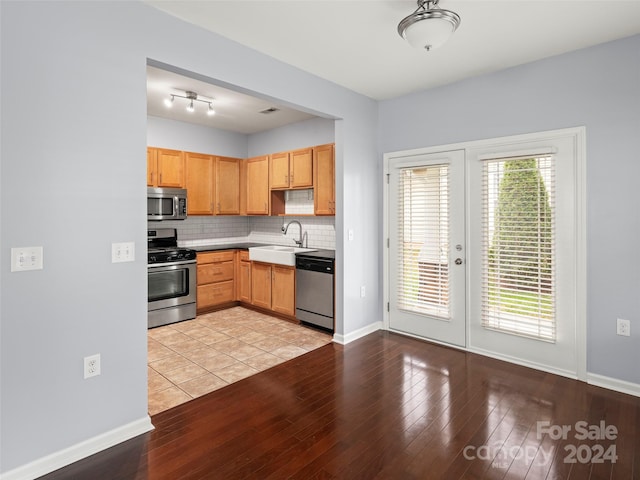 kitchen featuring stainless steel appliances, sink, light wood-type flooring, and backsplash