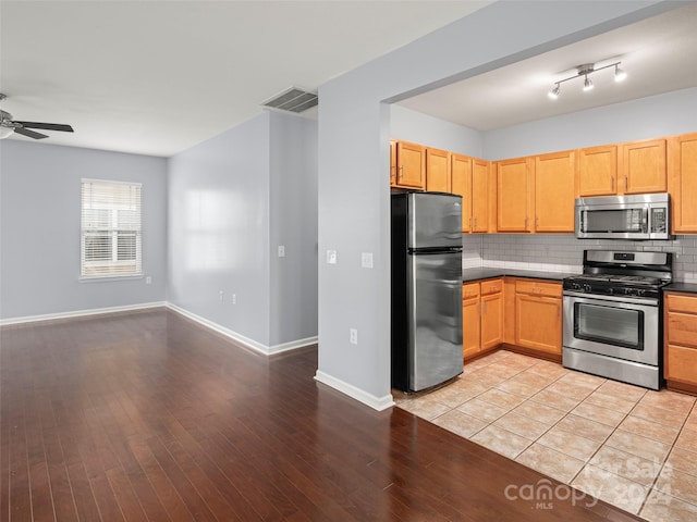 kitchen featuring stainless steel appliances, light hardwood / wood-style floors, ceiling fan, and backsplash