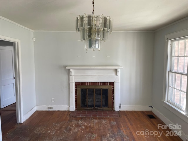 unfurnished living room featuring ornamental molding, an inviting chandelier, dark hardwood / wood-style floors, and a fireplace