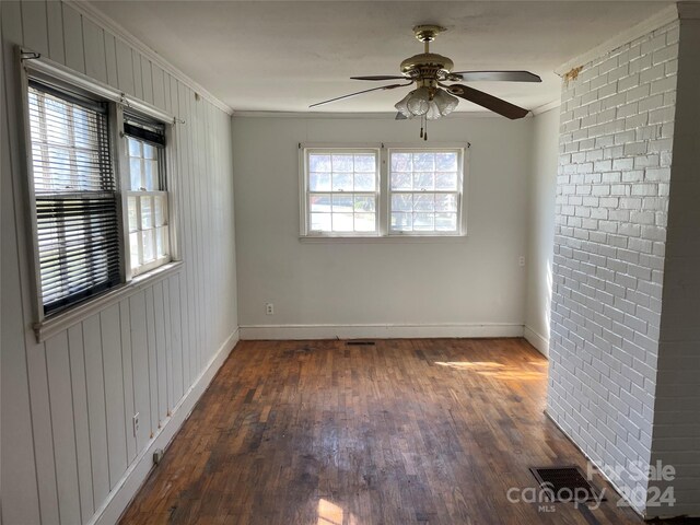 223 Chester Ave, Great Falls, SC 29055 - empty room featuring dark wood-type flooring, a ceiling fan, ornamental molding, baseboards, and brick wall