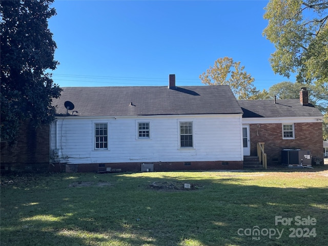 back of property featuring central AC and a yard