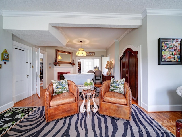 sitting room featuring ornamental molding, a textured ceiling, light hardwood / wood-style floors, and a brick fireplace