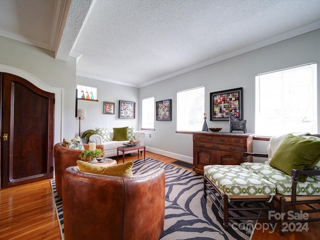 living room featuring ornamental molding, a textured ceiling, and light hardwood / wood-style floors