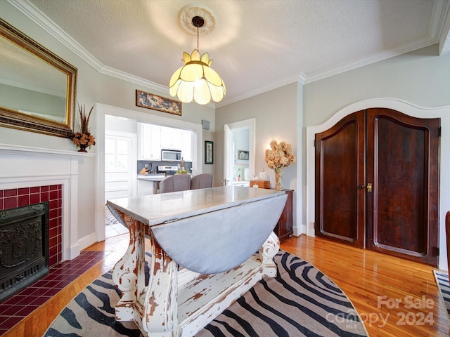 dining area featuring hardwood / wood-style floors, a fireplace, a textured ceiling, and crown molding