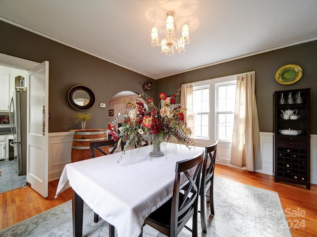 dining room with a chandelier, light wood-type flooring, and crown molding