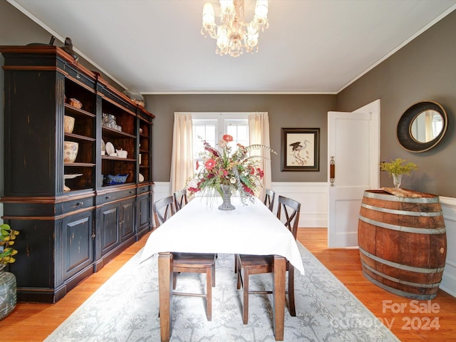 dining area featuring light wood-type flooring, a chandelier, and crown molding