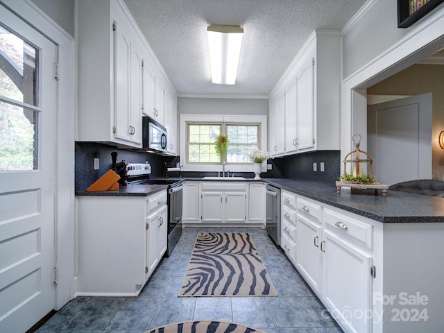 kitchen featuring white cabinetry, sink, dark tile patterned floors, appliances with stainless steel finishes, and ornamental molding