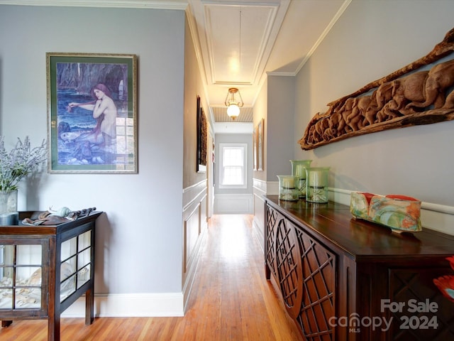 corridor with ornamental molding and light hardwood / wood-style flooring