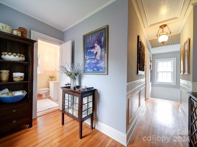 corridor with light hardwood / wood-style flooring and ornamental molding