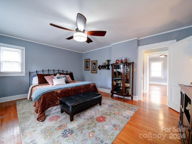 bedroom featuring light wood-type flooring, multiple windows, ceiling fan, and crown molding