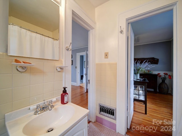 bathroom with wood-type flooring, vanity, and tile walls