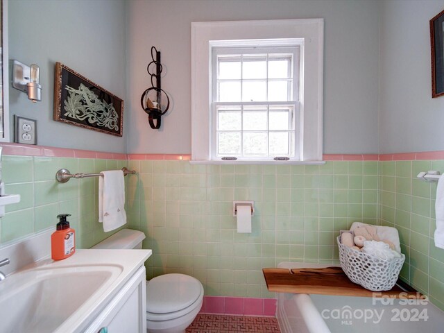 bathroom with toilet, vanity, tile walls, and tile patterned floors