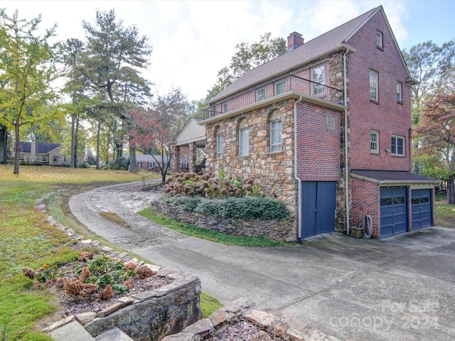 1116 E Franklin Blvd, Gastonia, NC 28054 - view of side of property with concrete driveway, a garage, stone siding, a balcony, and a chimney