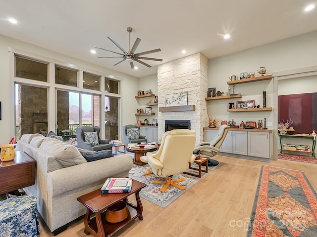 living room featuring a fireplace, ceiling fan, and light hardwood / wood-style flooring