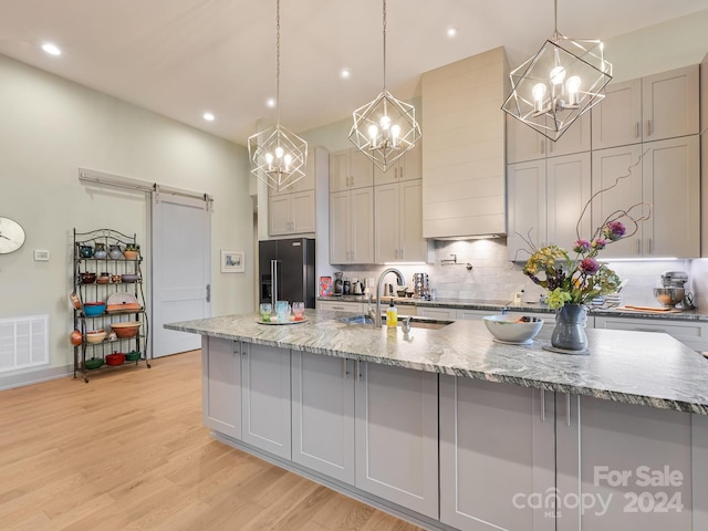 kitchen with pendant lighting, black refrigerator with ice dispenser, a barn door, and sink