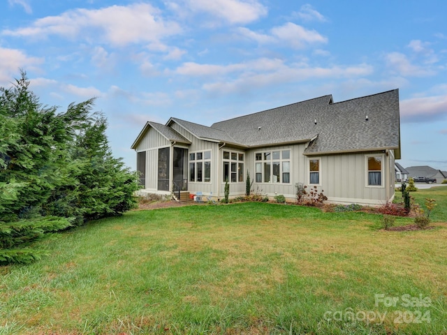 rear view of house with a sunroom and a yard